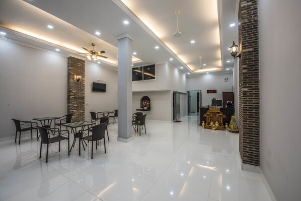 Amplia habitación, bien iluminada, con zona de comedor, chimenea y mostrador de recepción.