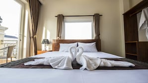 Una habitación de hotel con cama, mesita de noche, lámpara, ventana con cortinas y vistas al exterior.