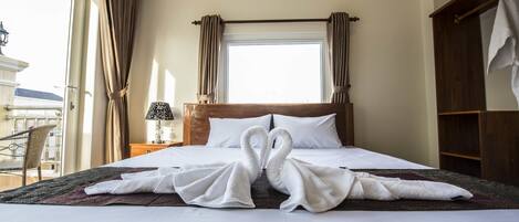 A hotel room with a bed, a nightstand, a lamp, a window with curtains, and a view of the outside.