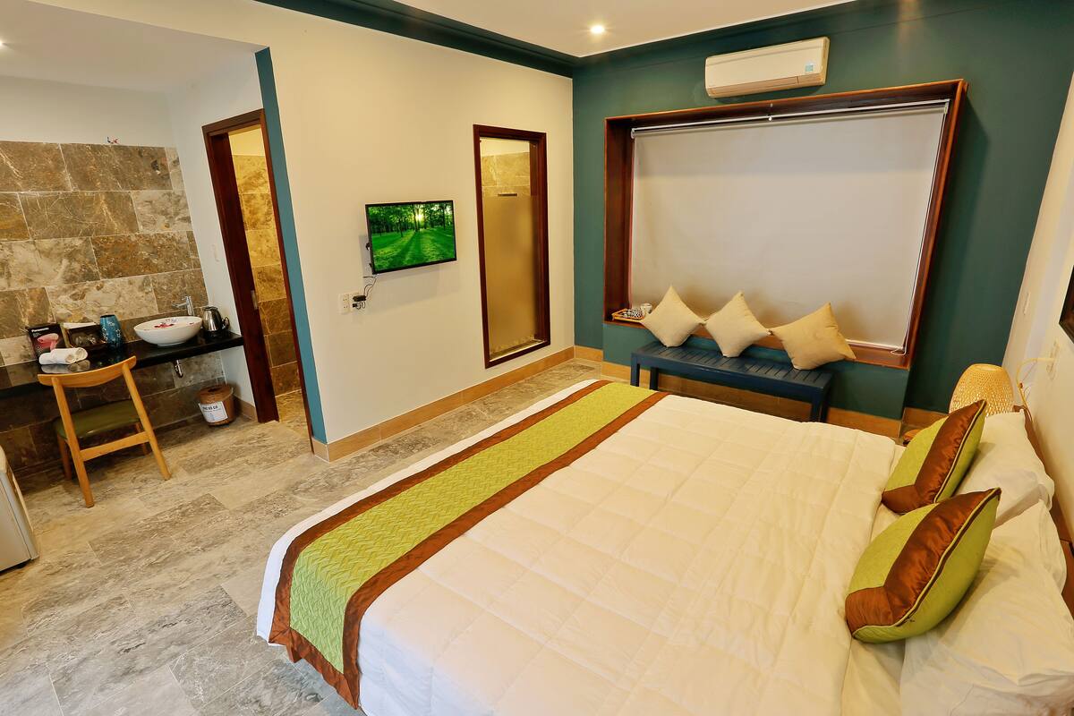 Un dormitorio con una cama grande, una mesita de noche, televisión y un baño con lavabo y ducha.