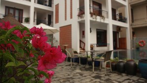 A multi-story building with balconies, outdoor seating, and potted plants.