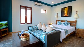 A bedroom with a bed, a sofa, a TV, and a small table with a plant.