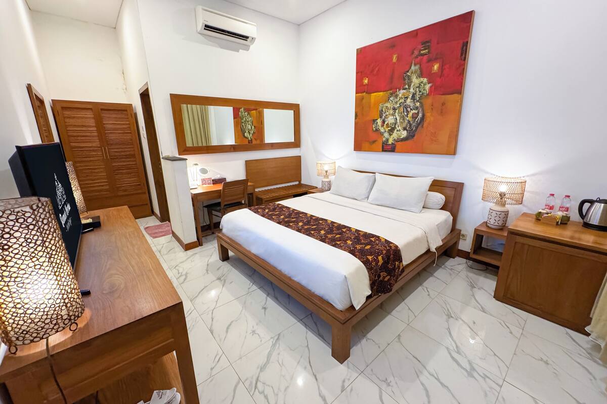Een hotelkamer met een bed, bureau, stoel en een groot schilderij aan de muur.