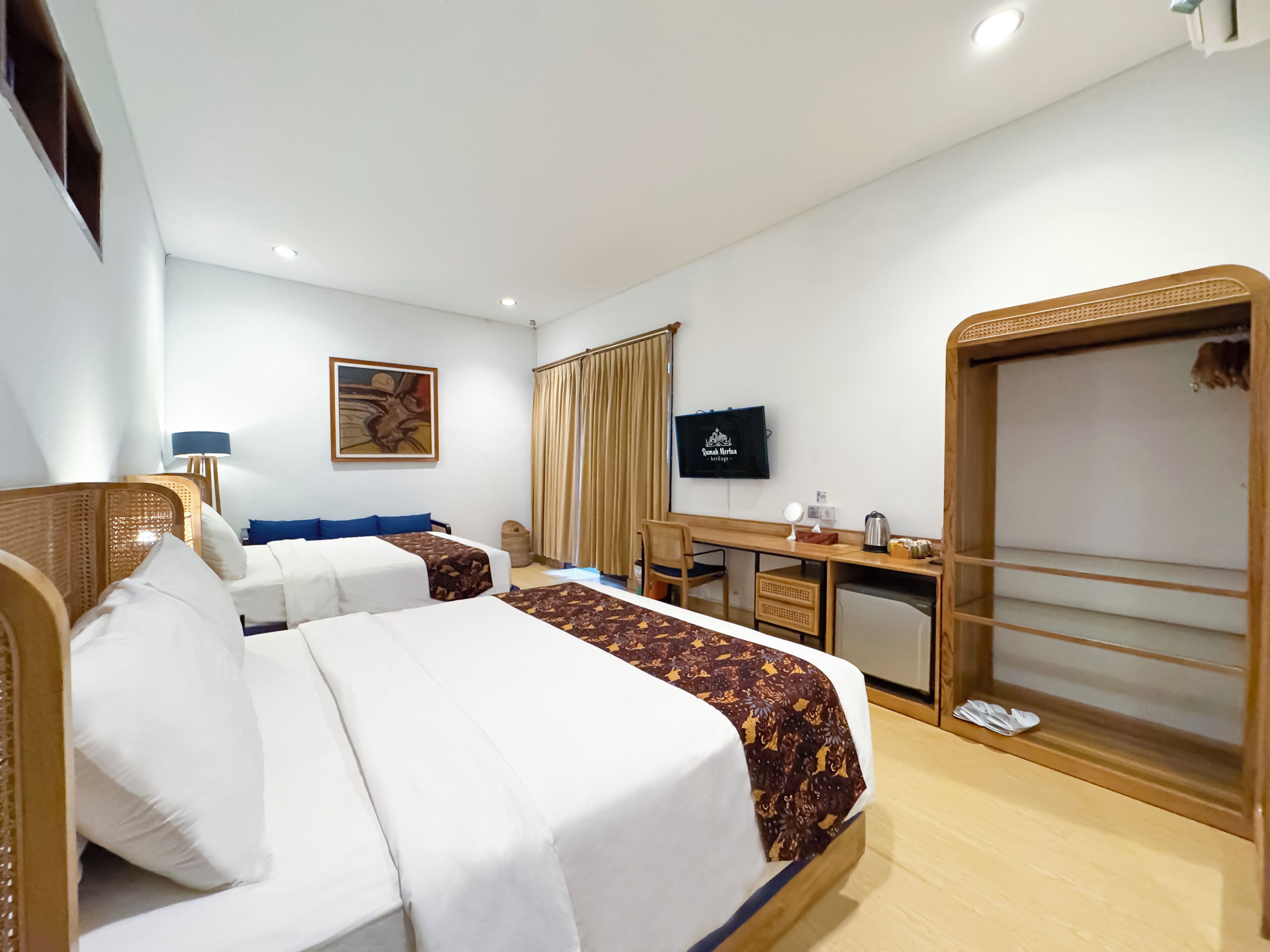 A hotel room with two beds, a desk, a television, and a large mirror.