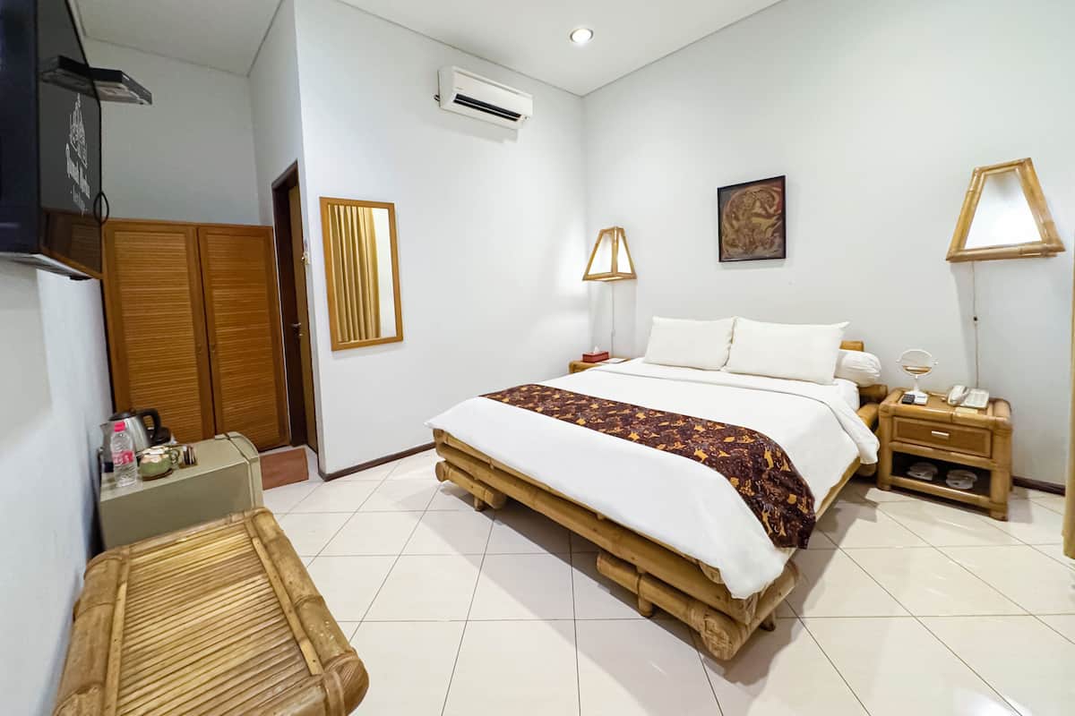 Een slaapkamer met een bed, nachtkastjes, een lamp, een airconditioner en een kledingkast.