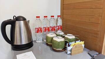 Una mesa con un hervidor, botellas de agua, tazas verdes y un menú.