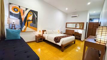 Una camera d'hotel con un letto, comodino, lampada, opere d'arte, scrivania, sedia e armadio.