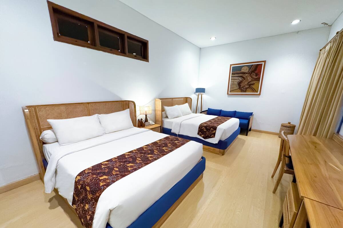 Een hotelkamer met twee bedden, een bureau, een lamp en een schilderij aan de muur.