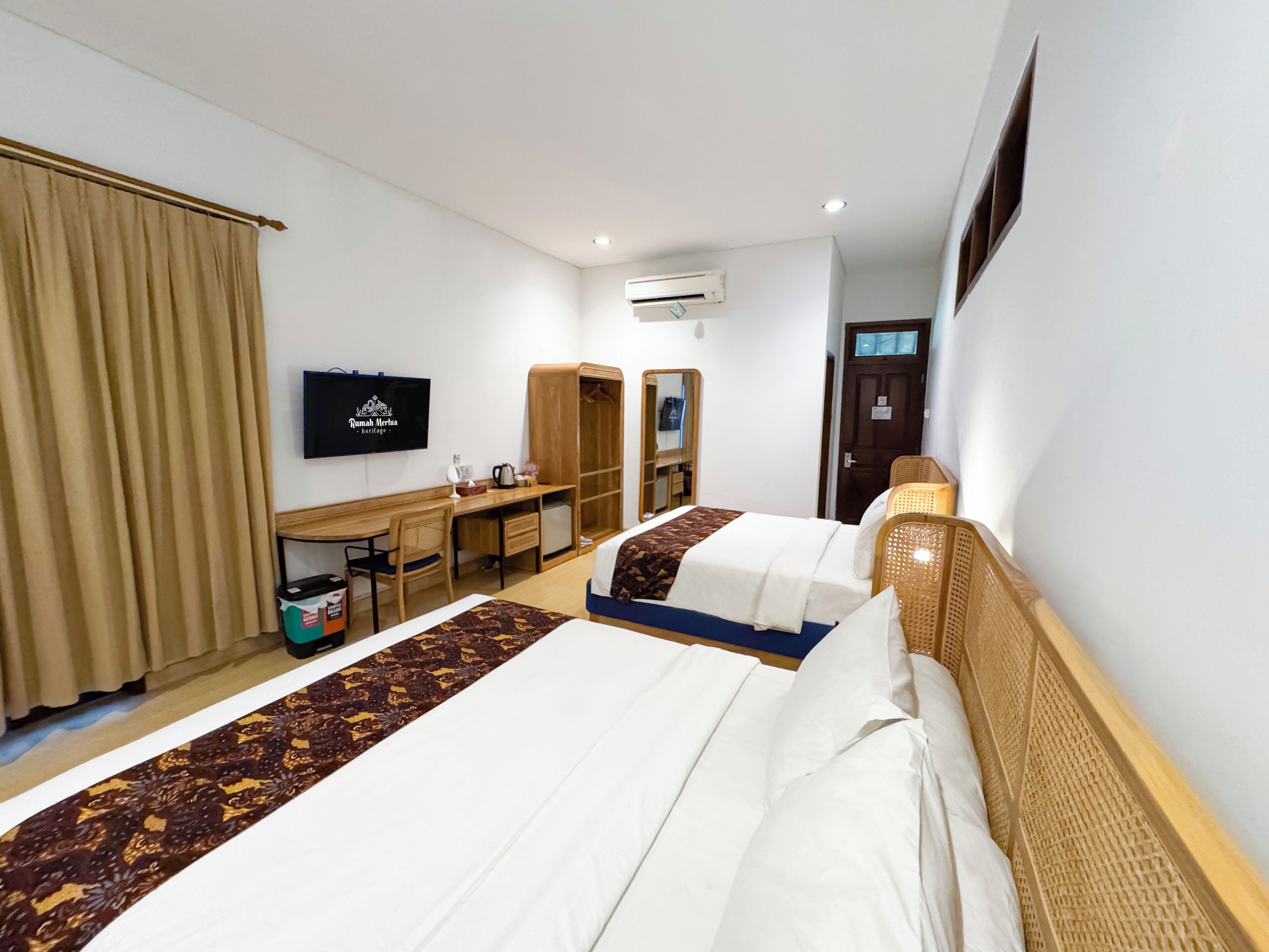 A hotel room with two beds, a desk, a TV, and a wardrobe.
