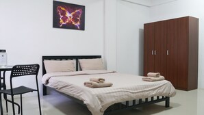 Un dormitorio con cama, una silla, armario y una obra de arte colgada en la pared.