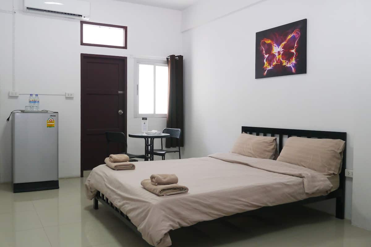 Une chambre d’hôtel équipée d’un lit, d’un bureau, d’une chaise, d’un réfrigérateur et d’une fenêtre.