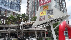 Un edificio moderno con varios pisos y un llamativo letrero de MaxValu.