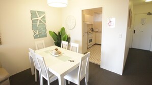 A dining area with a white table and chairs, a clock, a starfish decoration, and a plant. - Beachfront Shoal Bay (Nelson Bay)