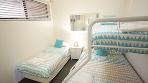 A bedroom with two single beds, a nightstand, a mirror, and a window with blinds. - Beachfront Shoal Bay (Nelson Bay)