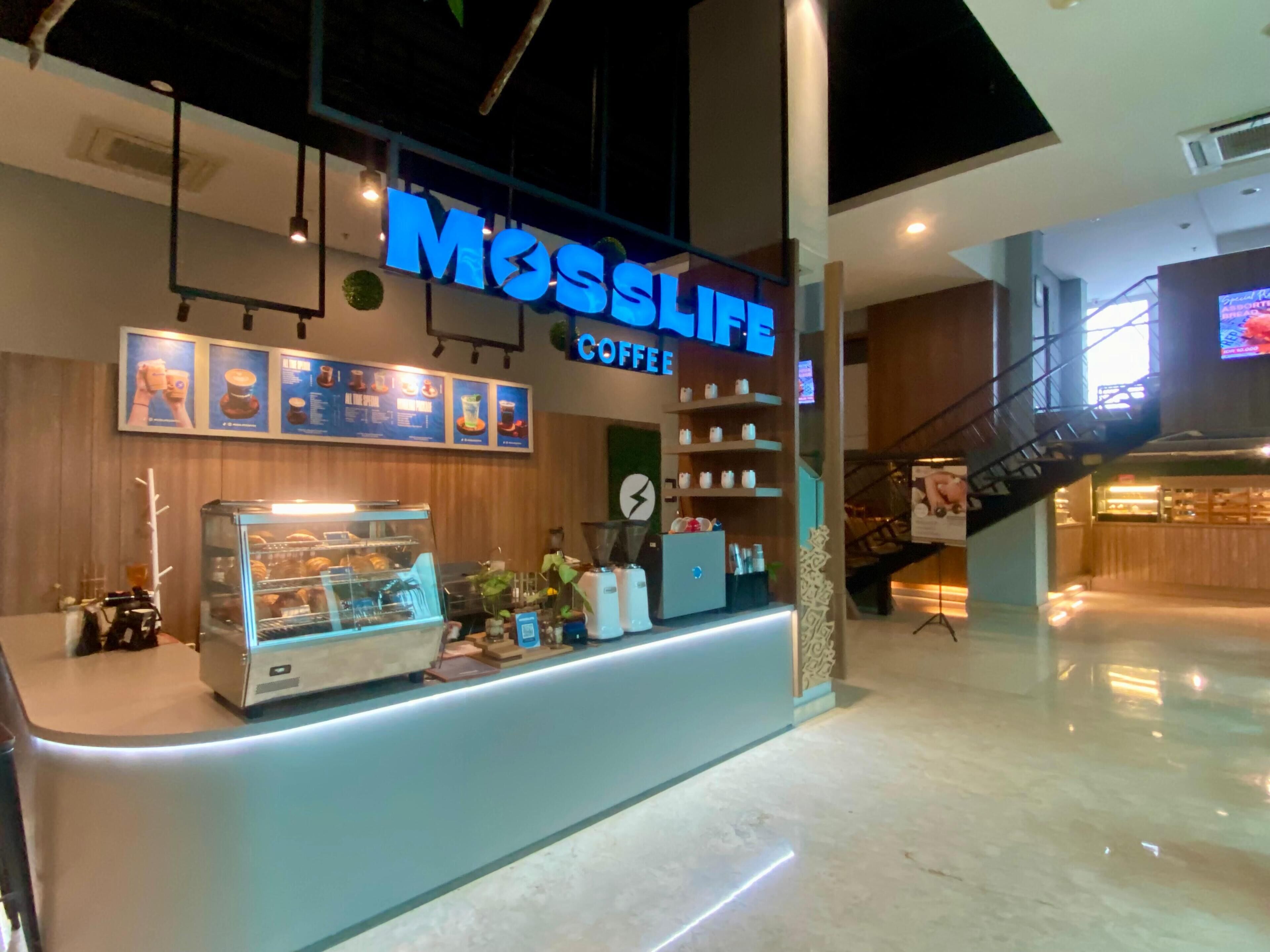 Una cafeteria anomenada Mosslife amb un interior modern, una vitrina amb pastissos i una escala al fons.
