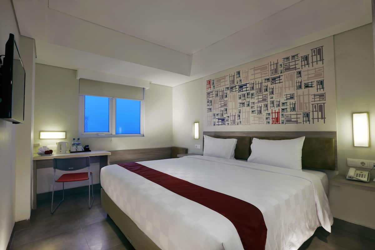 Habitación de hotel con cama, escritorio, silla y una gran obra de arte abstracta en la pared.