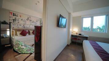 A hotel room with a bunk bed, a desk with a chair, a TV mounted on the wall, and a window with a view.