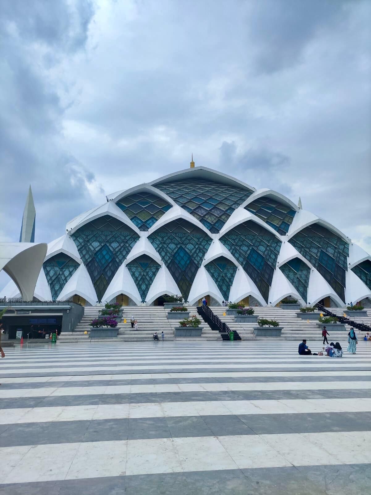 A modern architectural building with a unique geometric design, featuring a series of arched windows and a prominent spire.