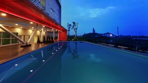 A modern hotel pool area with a red structure and glass railings. - Grand Cordela Hotel Bandung (Bandung)