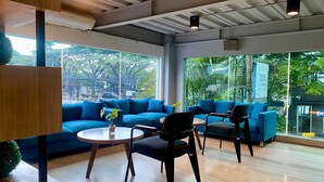 A modern interior with a blue sofa set, a round table, and black chairs. - Grand Cordela Hotel Bandung (Bandung)