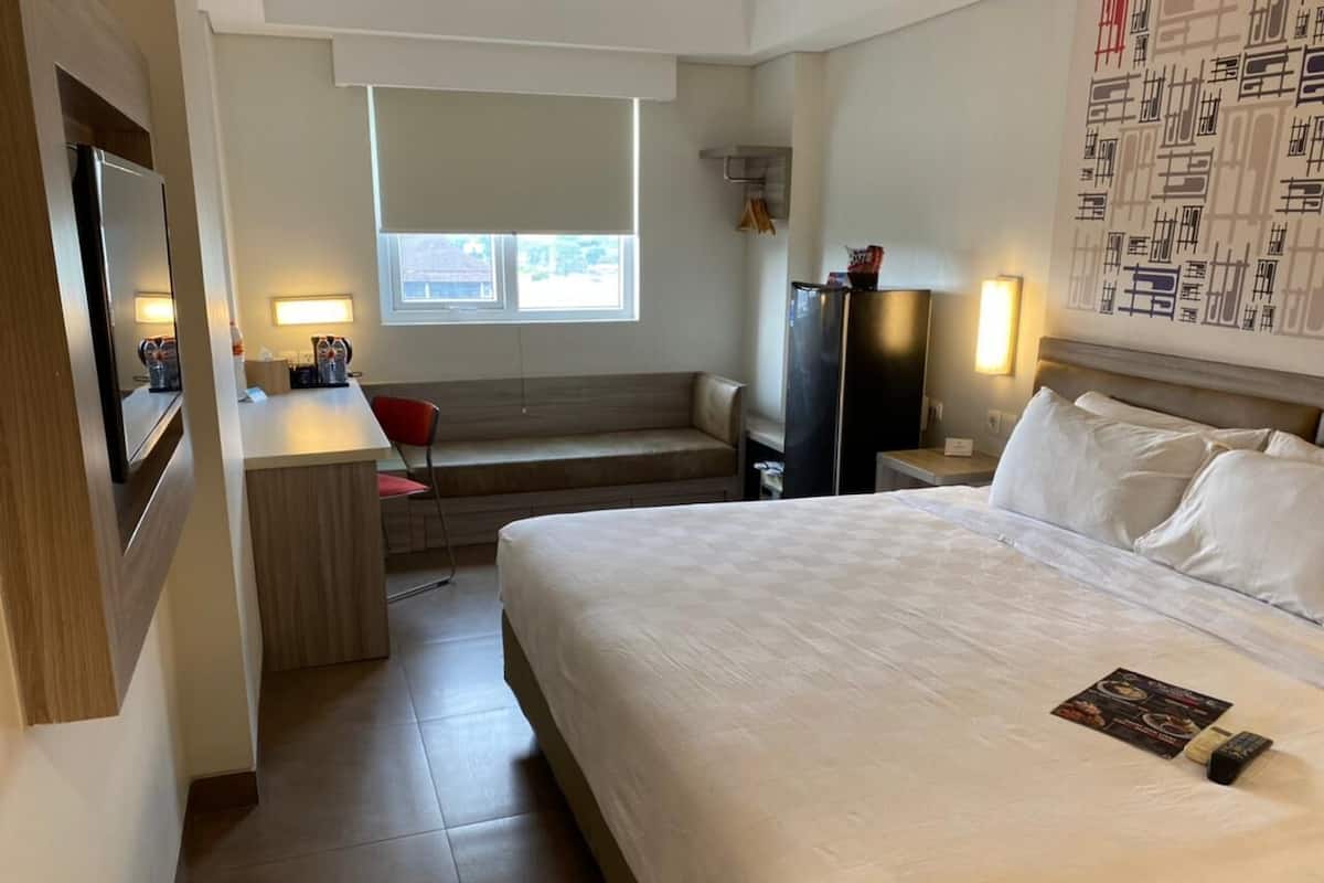 Una habitación de hotel con una cama, un escritorio, una silla, un televisor y una ventana.