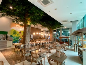 Un restaurante con árboles de interior, mesas y sillas de madera.