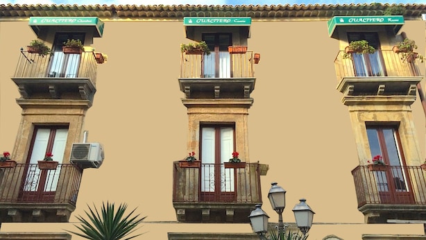 Un immeuble doté de nombreux balcons, chacun orné de plantes en pot et d’une enseigne portant le nom « GUATIERRO ».