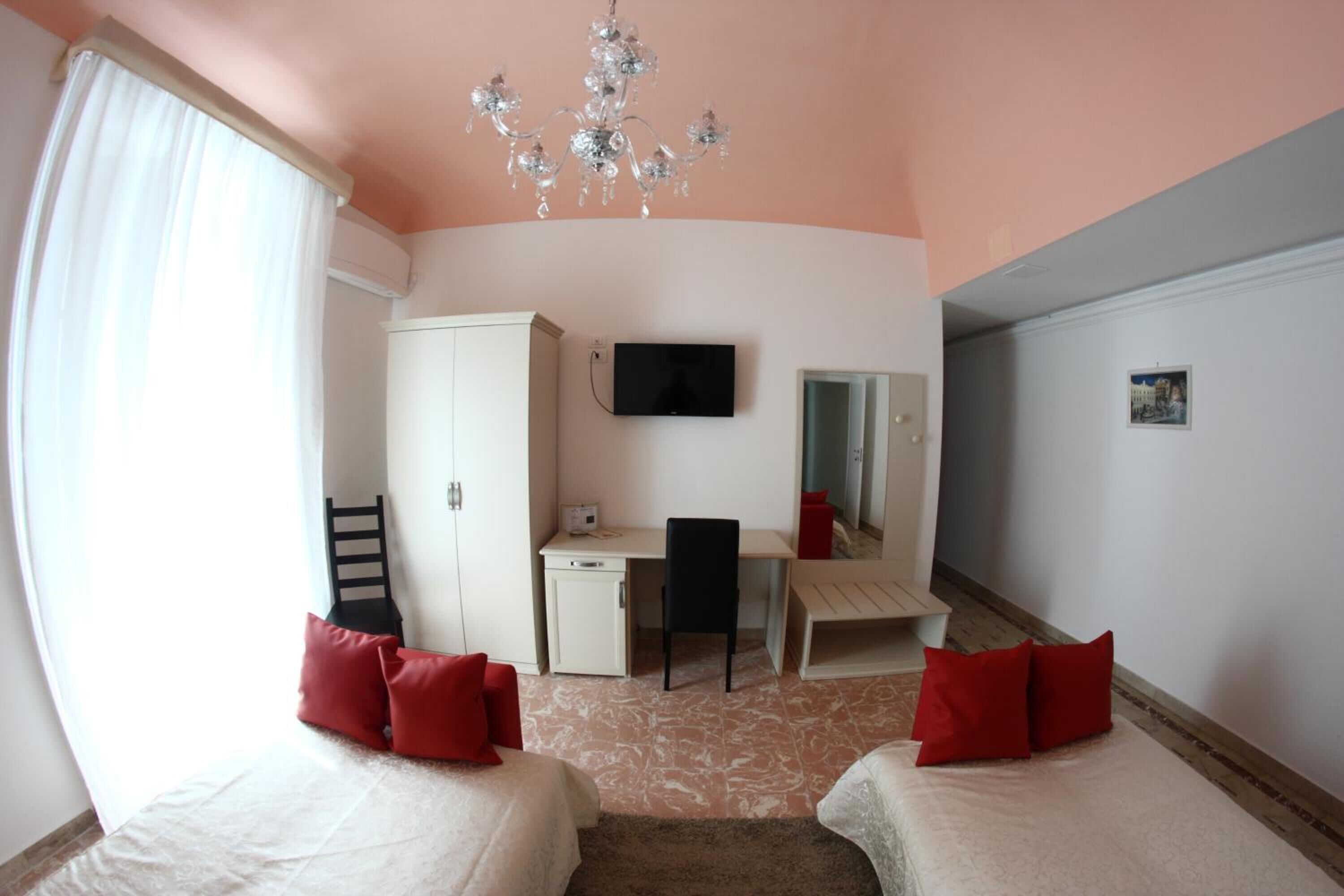 Une chambre avec deux lits, un bureau, une chaise, une télévision et un lustre.