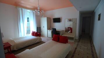 A hotel room with two beds, a desk, a TV, and a view of the outside.