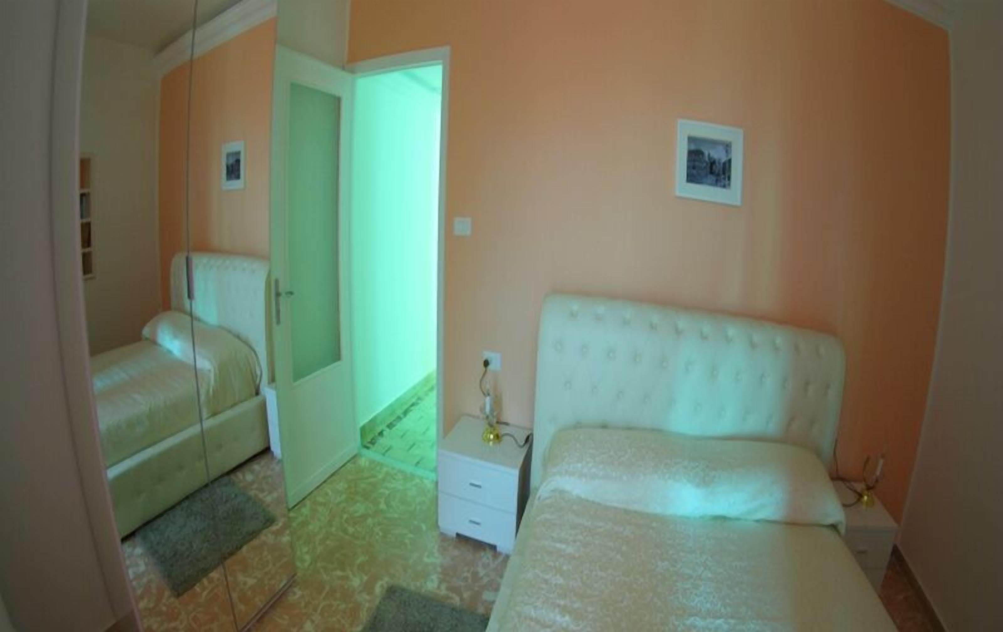 A bedroom with a bed, a nightstand, a chair, and a door leading to another room.