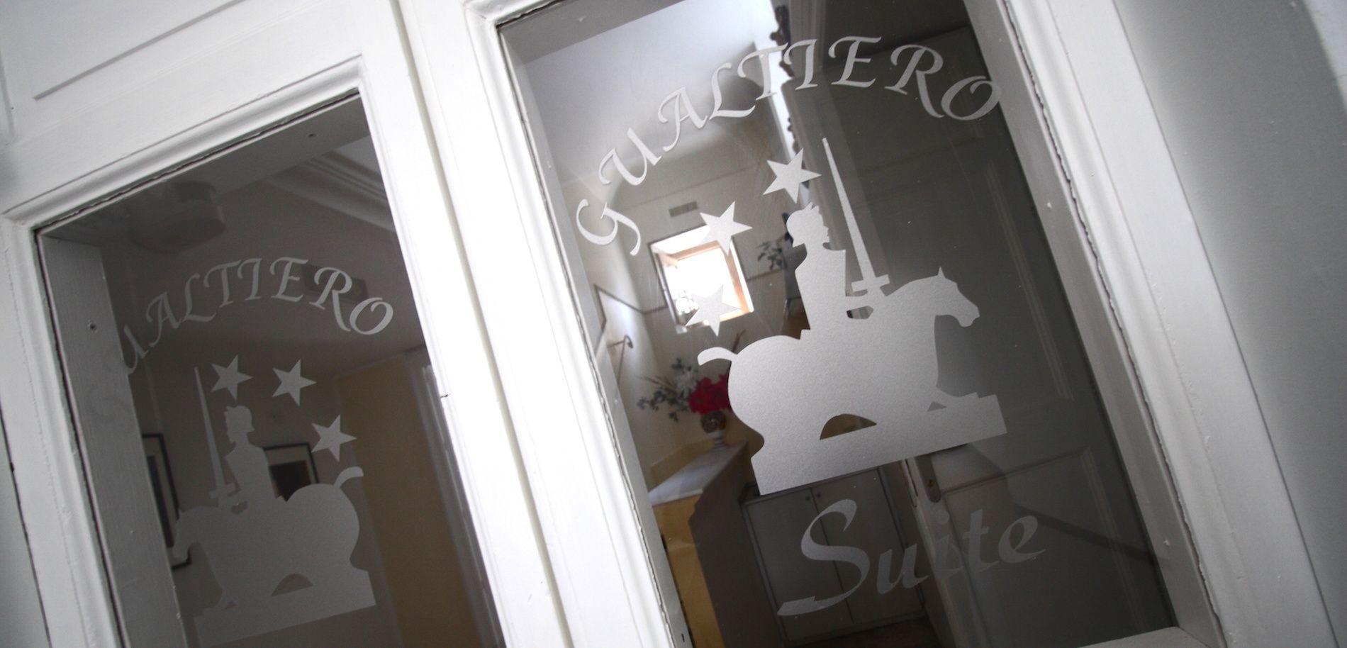 Een deur met geëtste glas, waarin silhouetten van een paard, sterren en de tekst 'SAINTER' zijn uitgesneden.