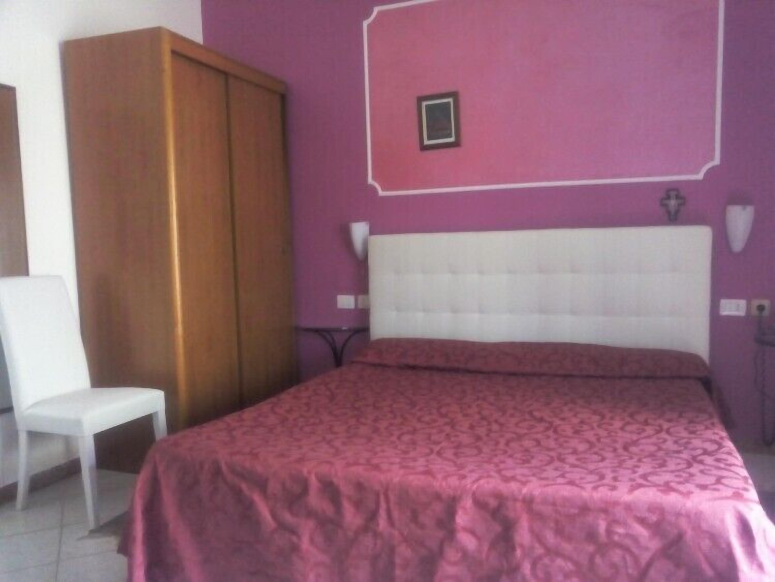 A bedroom with a bed, a wardrobe, and a chair.