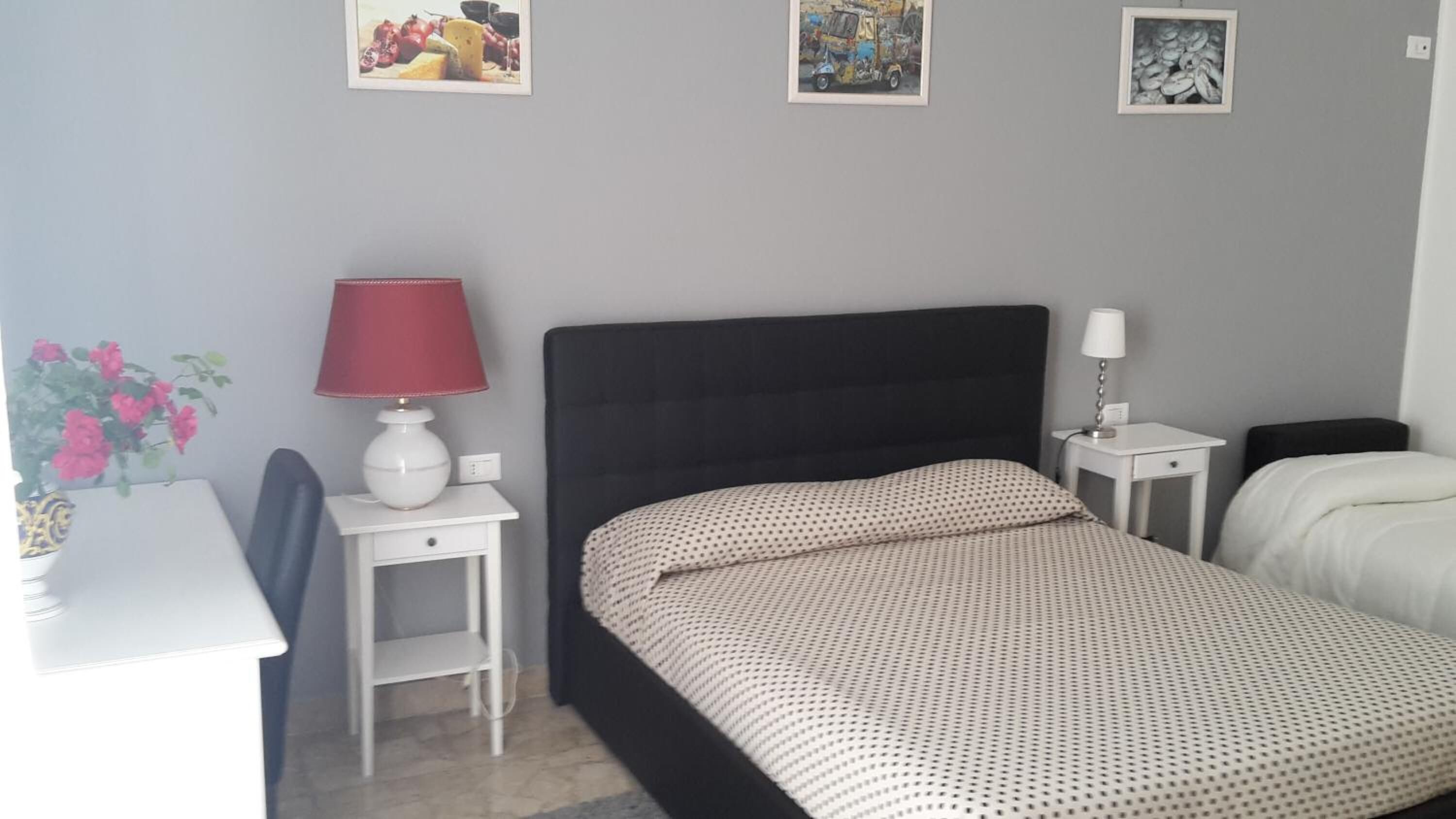 Un dormitorio ordenado con cama, mesitas de noche, un escritorio y una silla.