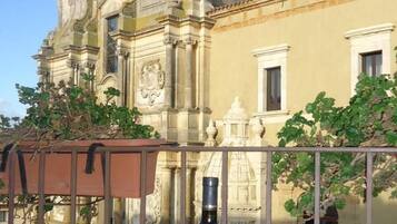 A table with a bottle of wine and two glasses, set against a backdrop of a historic building with ornate architecture.
