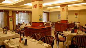 Un comedor con varias mesas y sillas, una zona de bar central y decoración mural.