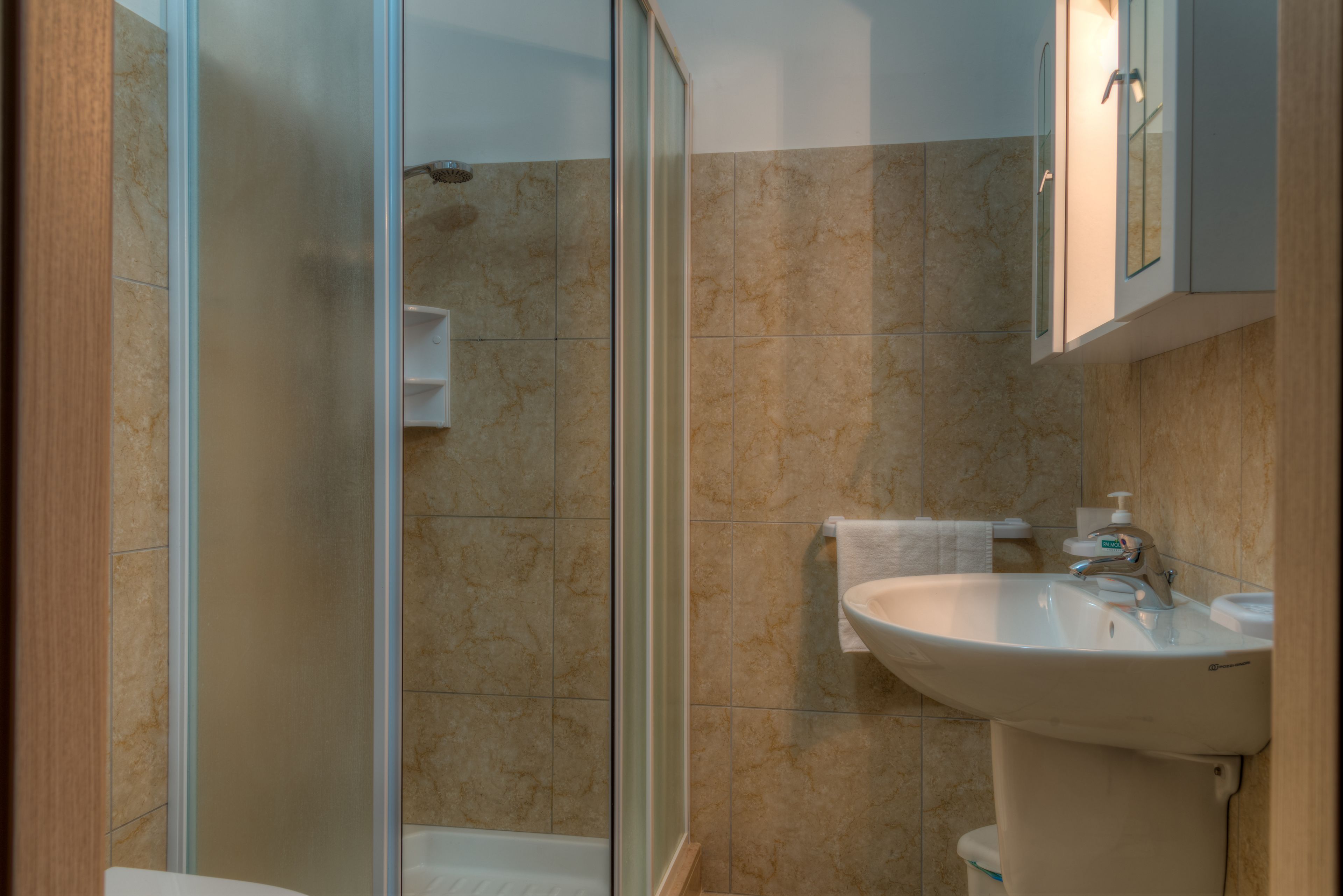 Un baño con cabina de ducha de vidrio, lavabo e inodoro.