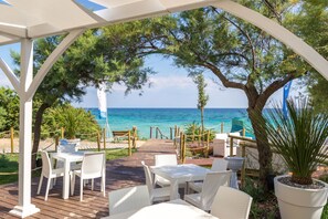 Un patio al aire libre con mobiliario de mimbre blanco, una terraza de madera y vista al mar.