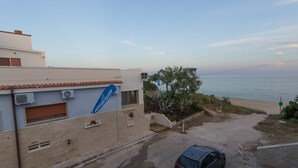 A building with a blue sign, a parked car, and a view of the sea. - Aquarium Residence (Manduria)