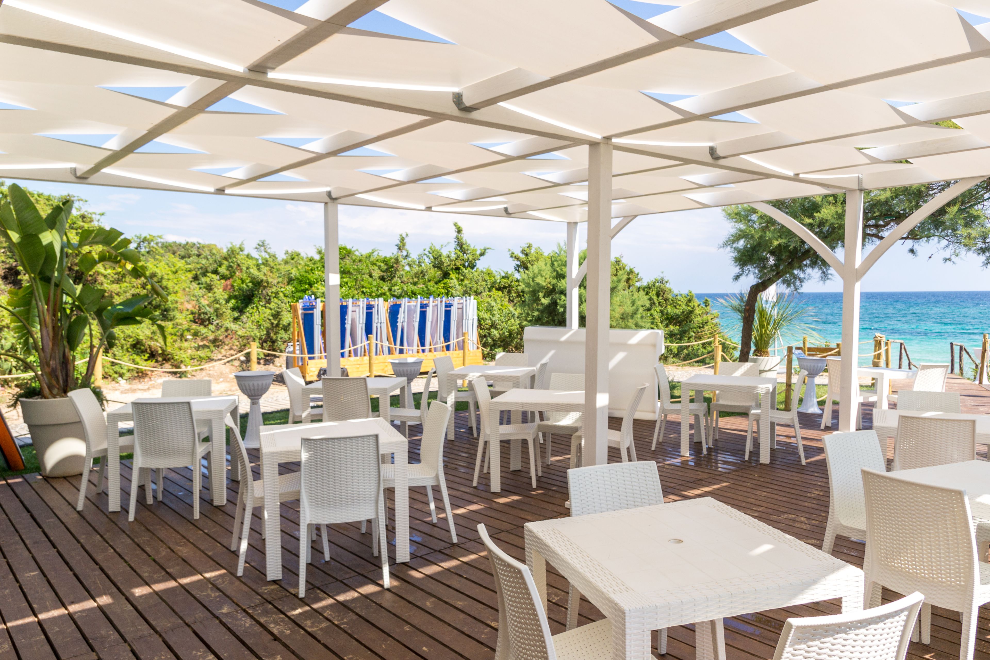 Une terrasse extérieure avec des meubles en osier blanc et une vue sur la mer.