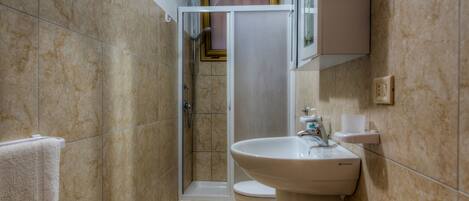 A bathroom with a shower, toilet, and sink.