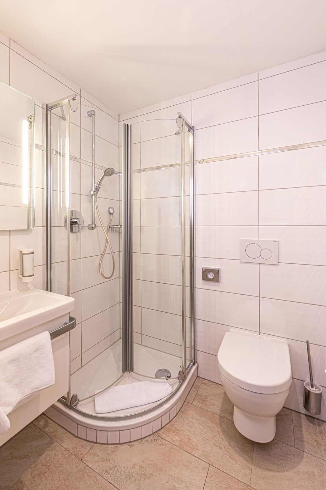 A modern bathroom with a glass-enclosed shower, a white sink, and a toilet.