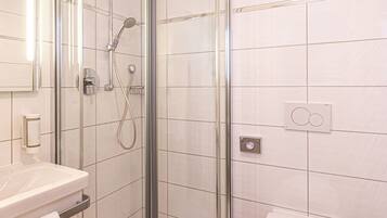 A modern bathroom with a glass-enclosed shower, a white sink, and a toilet.