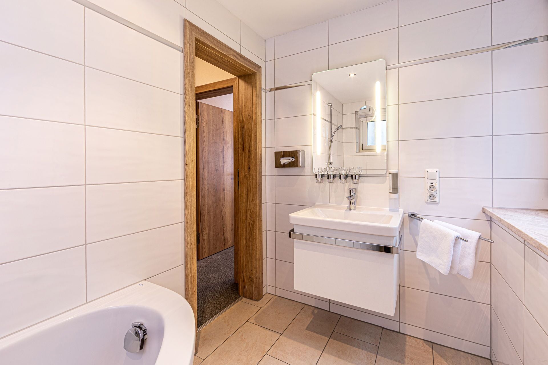 A modern bathroom with a bathtub, a sink, and a mirror.