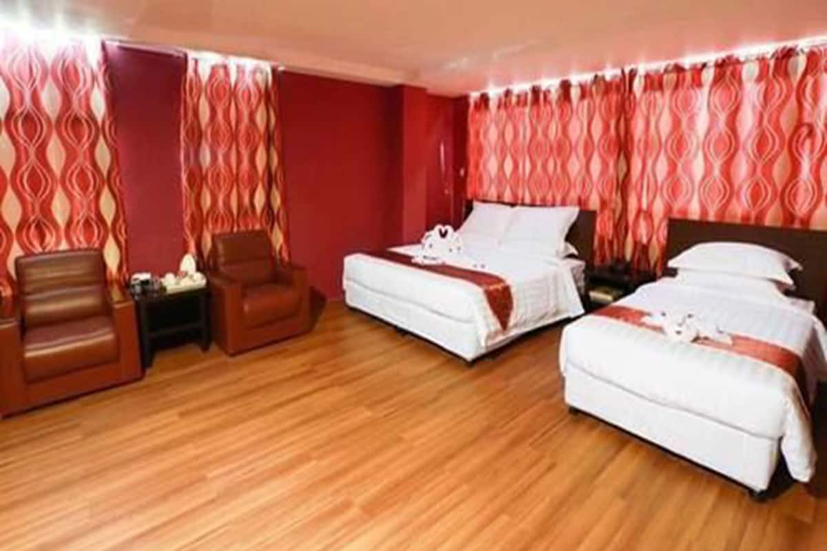 Une chambre d’hôtel avec deux lits, un plancher en bois et des rideaux rouges à motifs.