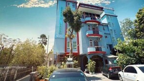 Un hotel de varios pisos con un llamativo letrero 'HOTEL' en la fachada, que presenta un diseño arquitectónico moderno con balcones y ventanas amplias.