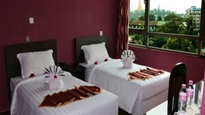 Habitación de hotel con dos camas, una ventana con vista a la ciudad y una mesita con artículos de tocador.