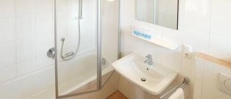A modern bathroom with a glass-enclosed shower, a white sink, and a mirror above the sink.