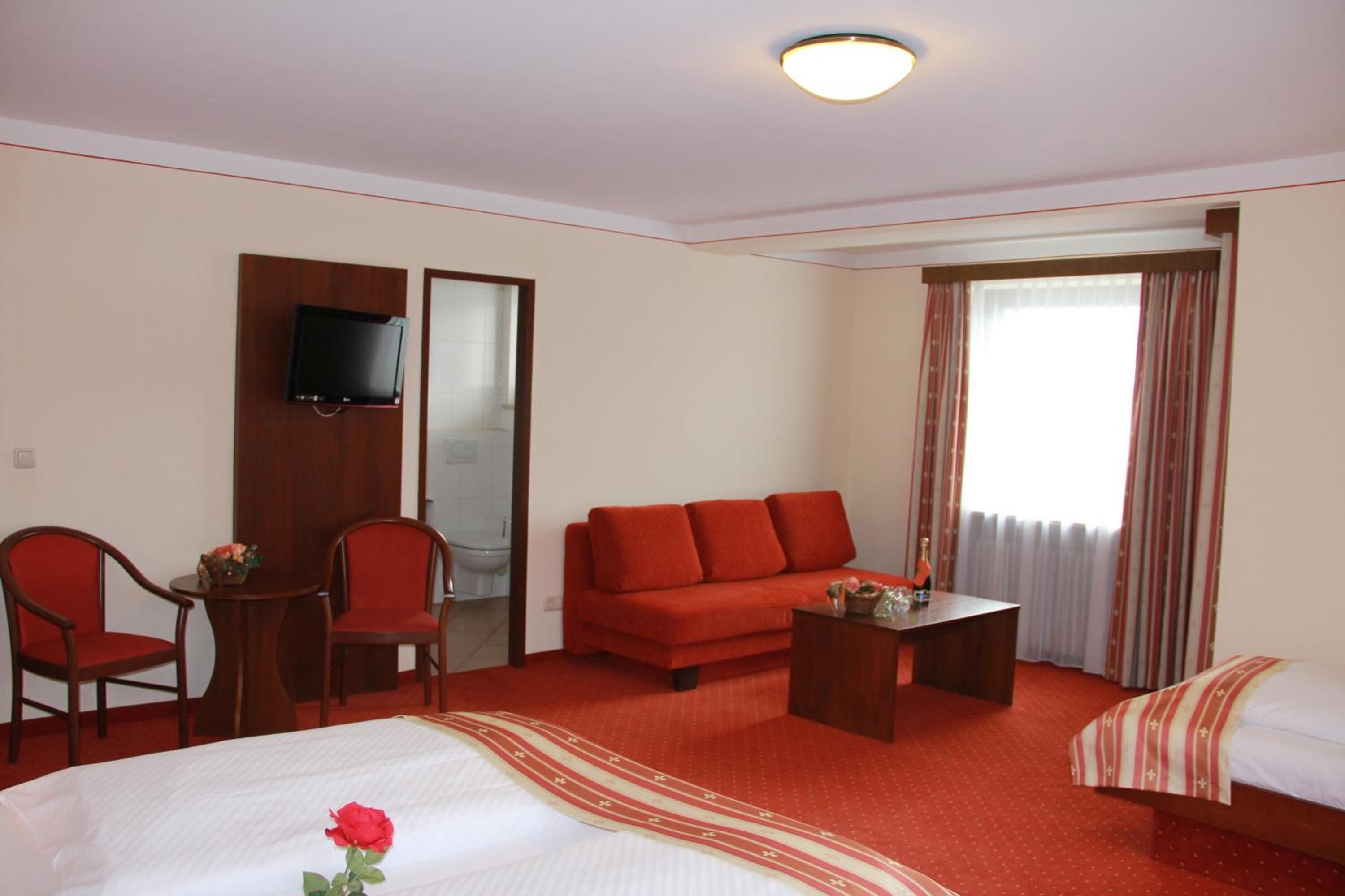 Una habitación de hotel con una cama, un sofá, una mesita y un televisor montado en la pared.