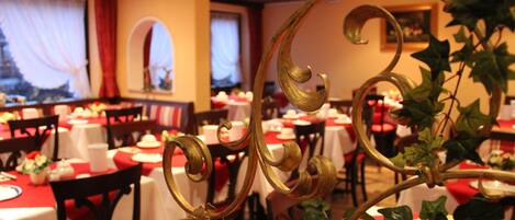 Un restaurante con mesas dispuestas para comer, con manteles rojos y detalles decorativos dorados.