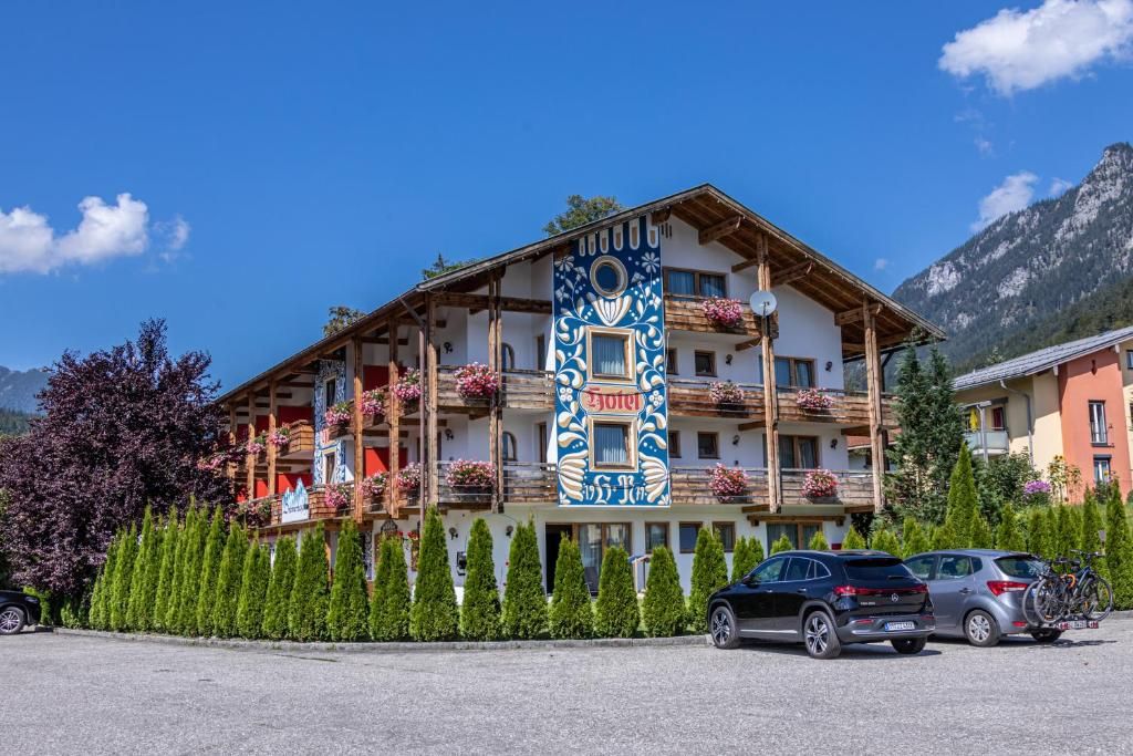 A hotel with multiple balconies, a prominent vertical sign, and a mountainous backdrop.